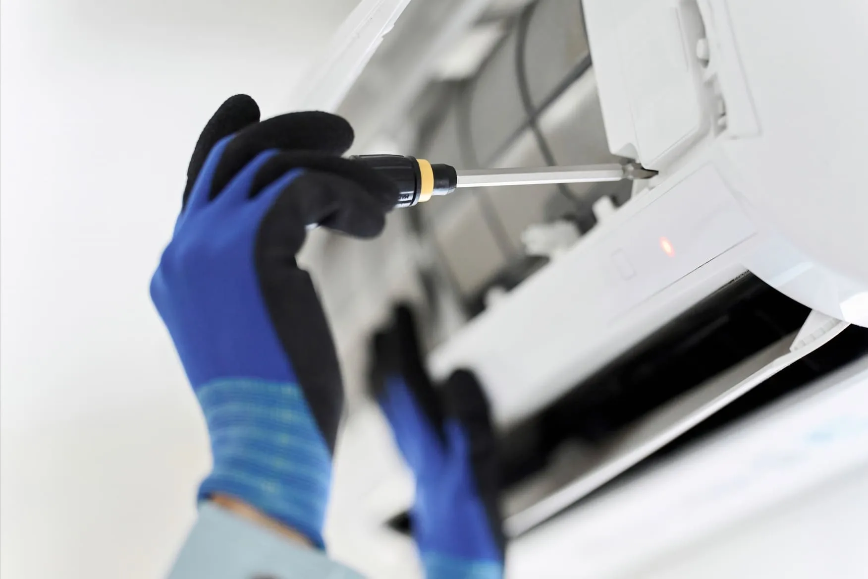 Uma pessoa usando luvas segurando uma chave de fenda - tabela de erros midea