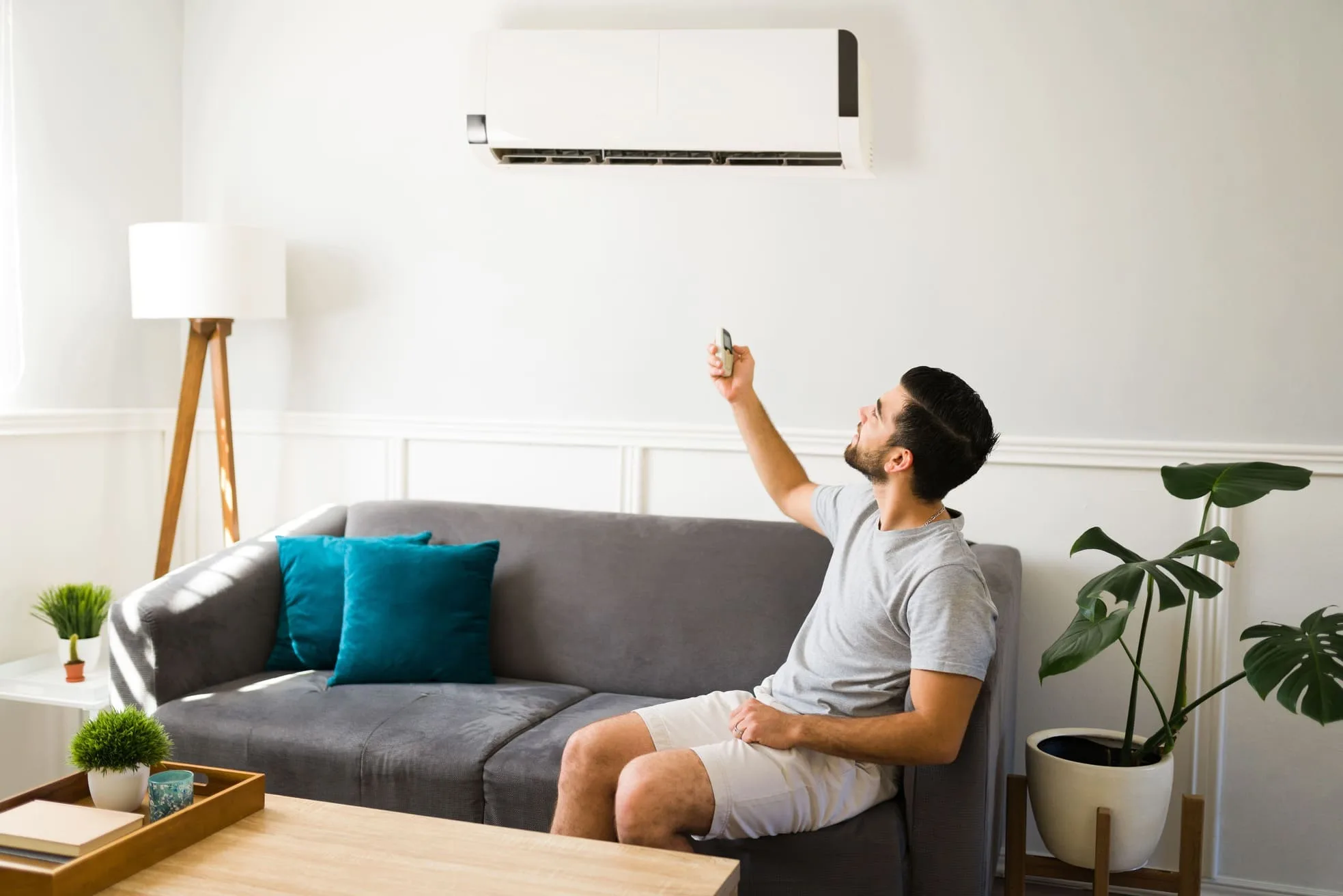 Homem sentado no sofá ligando ar-condicionado Consul